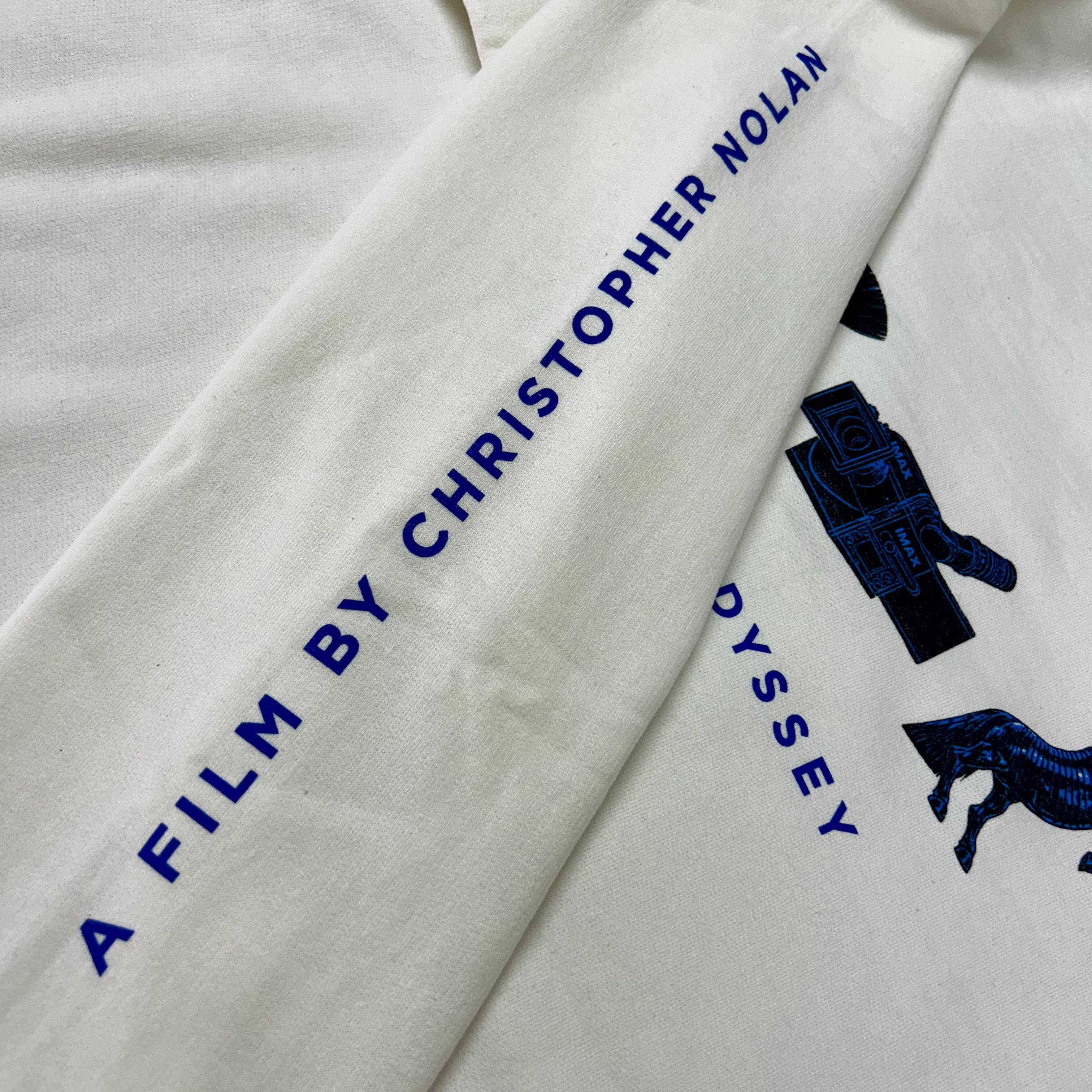 White fabric with blue text and graphics, including 'A Film by Christopher Nolan' and a camera icon.