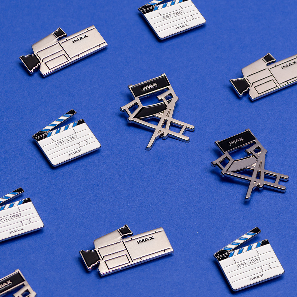 Several director’s chair, IMAX camera, and clapper board pins placed against a blue backdrop.