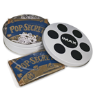 A white popcorn canister designed to resemble a film reel with an IMAX logo on the lid, with two unpopped bags of popcorn inside.
