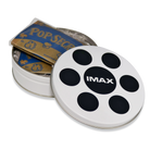 A white popcorn canister designed to resemble a film reel with an IMAX logo on the lid, with two unpopped bags of popcorn inside.