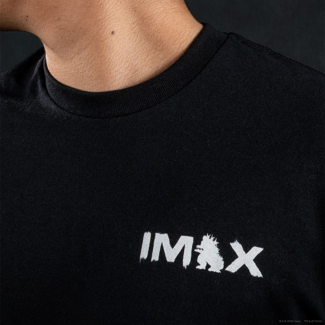 Close-up of a person wearing a black crew-neck t-shirt with a white distressed 'IMAX' logo printed on the chest.