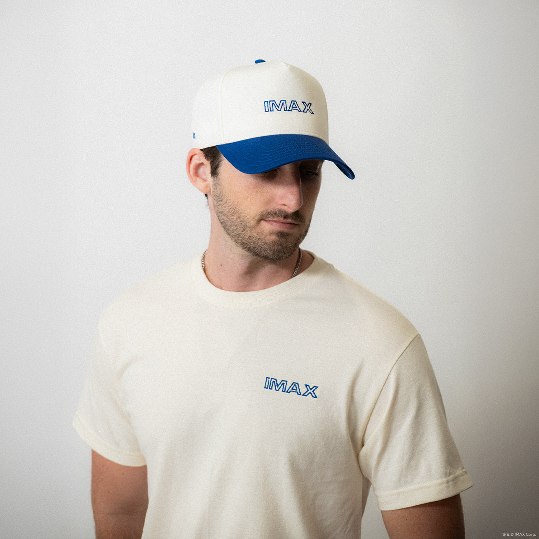 Man wearing a white cap and t-shirt with 'IMAX' logo on a plain background