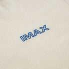 close up shot of the blue imax logo on a cream background of the hat.