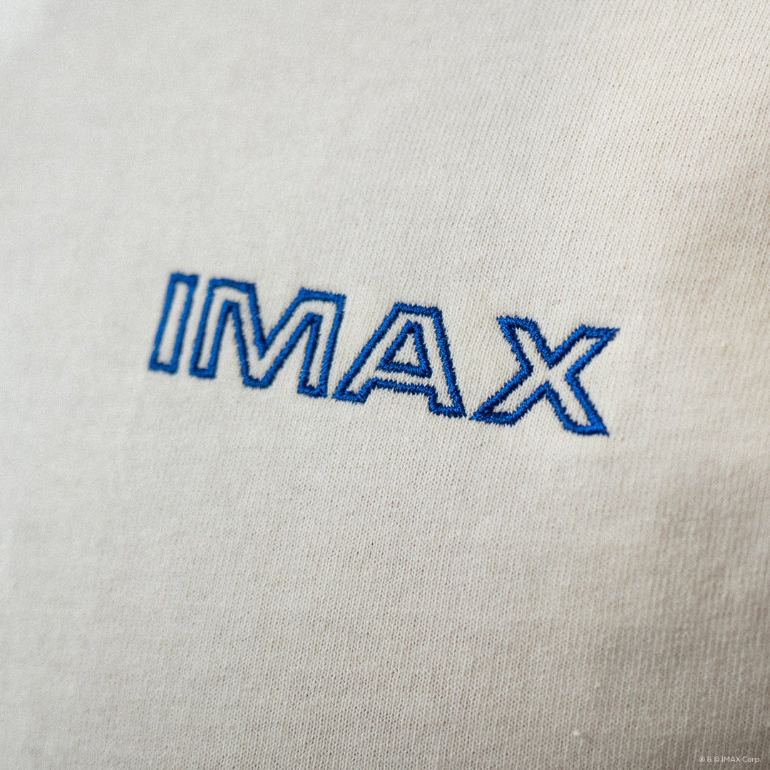 Close-up of 'IMAX' logo embroidered on a light gray fabric background