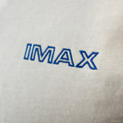 Close-up of 'IMAX' logo embroidered on a light gray fabric background